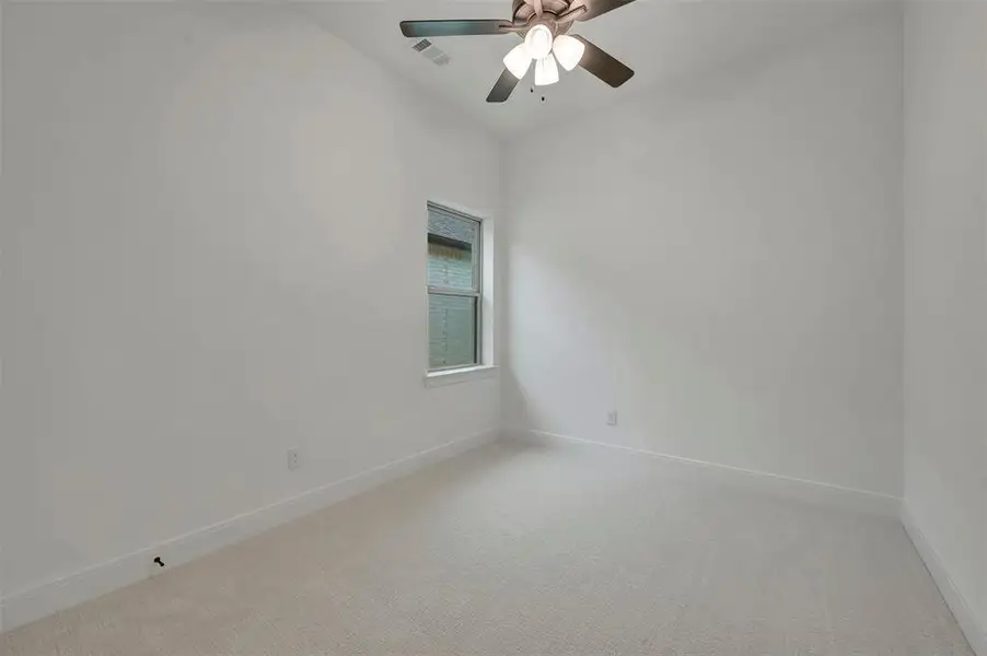 Neutral carpeted room featuring a ceiling fan with integrated lighting, a window with white trim, white baseboards, and light-toned walls