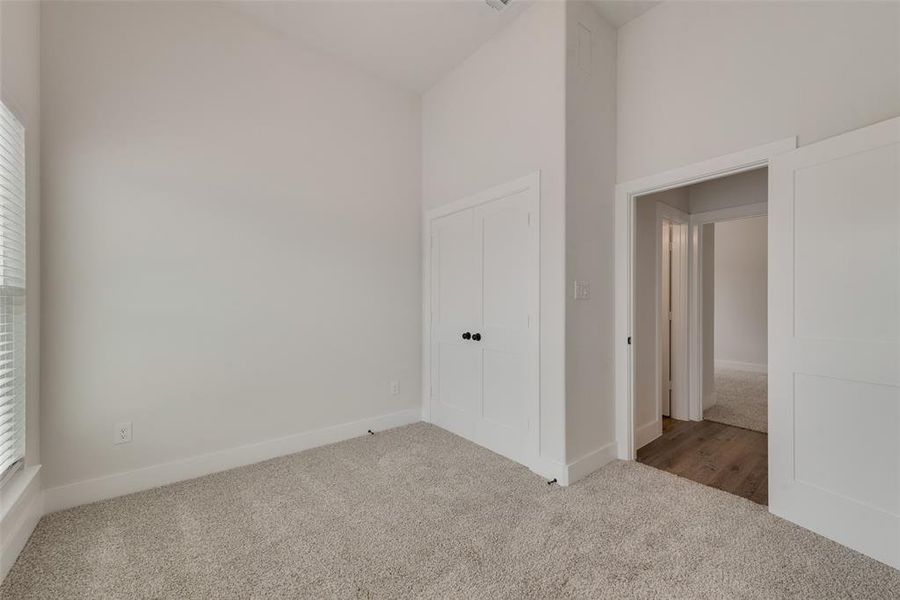 Unfurnished bedroom featuring carpet floors and high vaulted ceiling