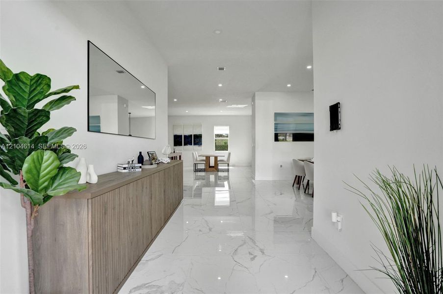 Expansive hallway with polished tile flooring, recessed lighting