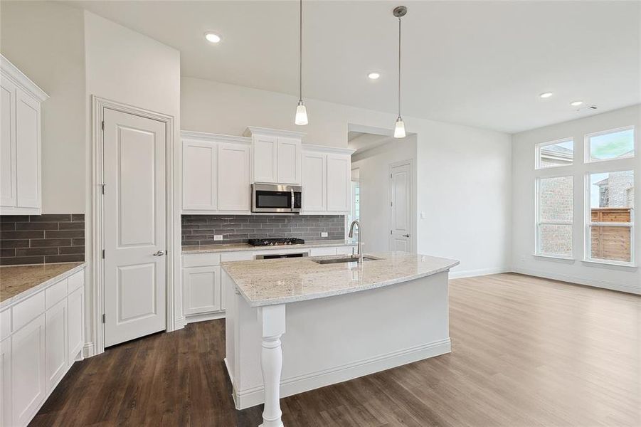 Kitchen with dark wood-type flooring, white cabinets, stainless steel appliances, a kitchen island with sink, and sink