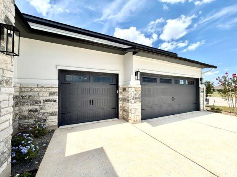 A welcoming front exterior features a stone and stucco facade with dual garage doors and ample parking space. A welcoming front exterior features a stone and stucco facade with dual garage doors and ample parking space.