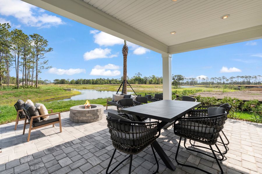 Kenai Model Home Covered Patio with Table and Chairs and Firepit at Reserve East in Flagler Beach