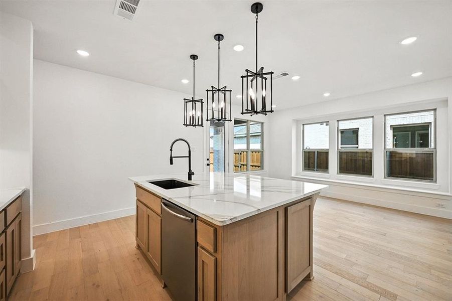 Kitchen featuring brown cabinets, pendant lighting, light wood-type flooring, stainless steel dishwasher, and recessed lighting Kitchen featuring brown cabinets, pendant lighting, light wood-type flooring, stainless steel dishwasher, and recessed lighting