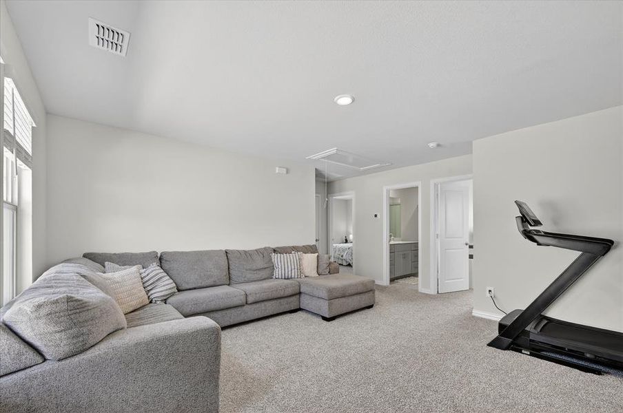 Carpeted living area featuring attic access and baseboards