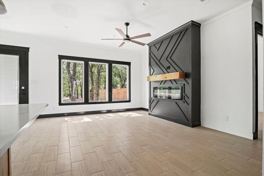 Unfurnished living room featuring ornamental molding, healthy amount of natural light, wood tiled floors, a ceiling fan, and recessed lighting