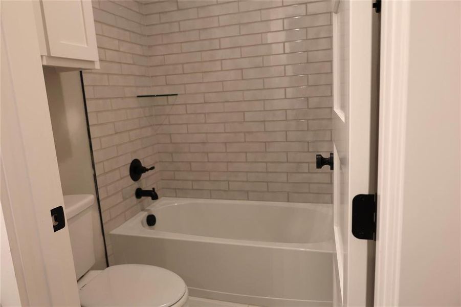 Bathroom featuring tiled shower / bath combo and toilet