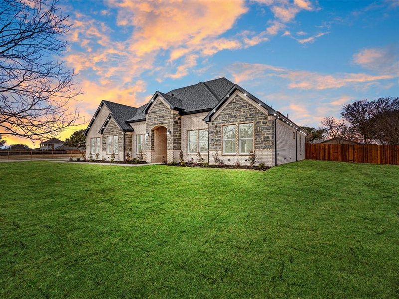 French country inspired facade with brick siding, stone siding, and roof with shingles