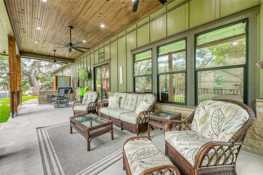 Expansive covered patio featuring a wood-finish plank ceiling with recessed lighting and ceiling fans