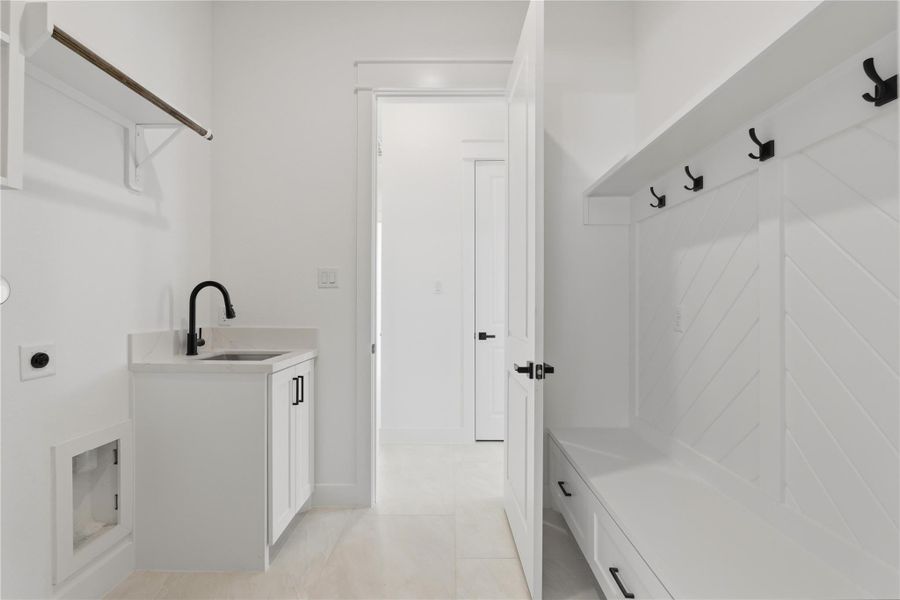 Step in from the garage to a spacious laundry room featuring a sink with extra storage and a handy mud area — perfect for hanging jackets, storing shoes, and keeping everyday essentials organized.