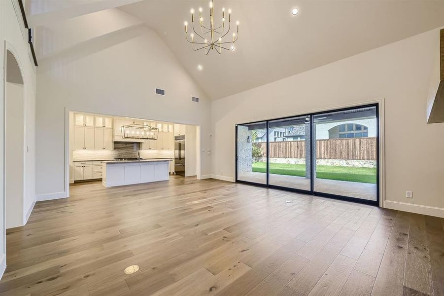 Living room with high vaulted ceiling, a chandelier, and multi-sliding glass patio doors