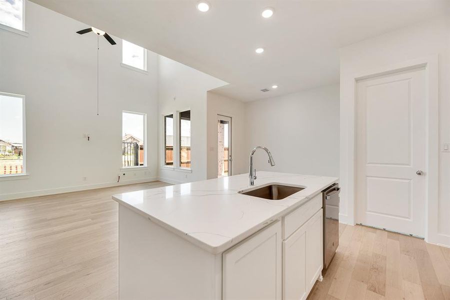 Kitchen featuring white cabinetry, recessed lighting, a kitchen island with sink, light wood-type flooring, and light stone counters Kitchen featuring white cabinetry, recessed lighting, a kitchen island with sink, light wood-type flooring, and light stone counters