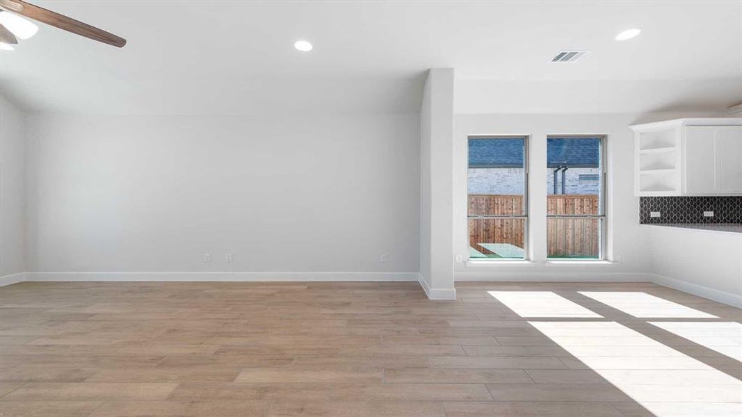 Empty room with ceiling fan and light hardwood / wood-style floors