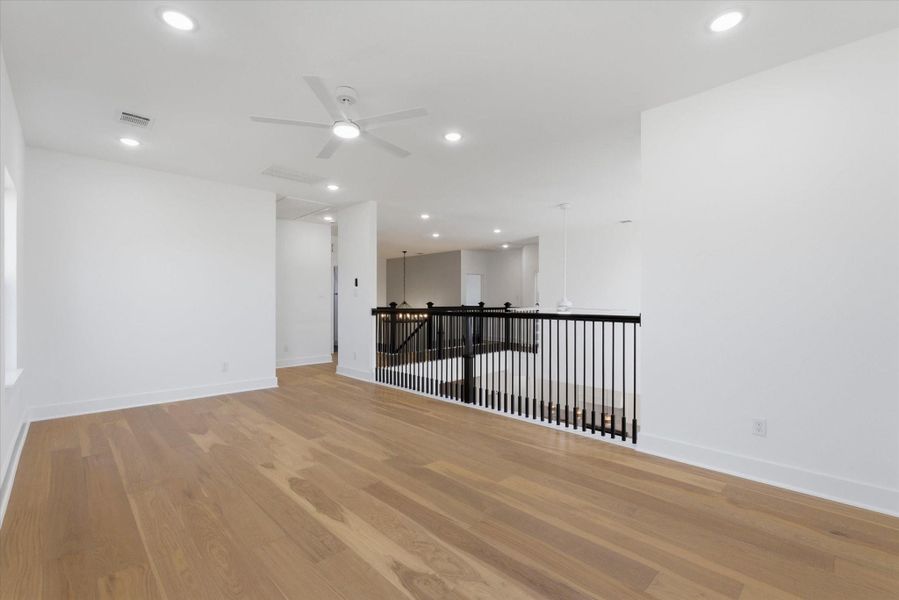 Upstairs, you’ll find a large game room featuring rich hardwood flooring, a ceiling fan, and recessed lighting that creates a bright, inviting space.