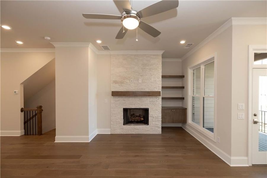 Unfurnished living room featuring recessed lighting, dark wood-type flooring, ornamental molding, a fireplace, and ceiling fan