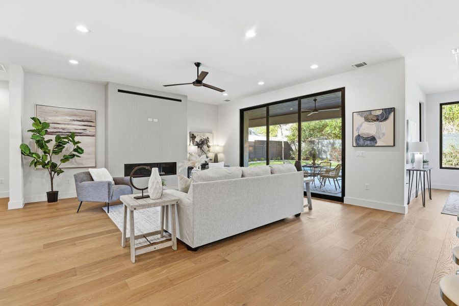 Living room featuring a premium fireplace, ceiling fan, recessed lighting, light wood finished floors, and plenty of natural light Living room featuring a premium fireplace, ceiling fan, recessed lighting, light wood finished floors, and plenty of natural light