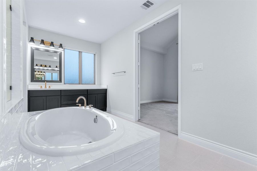 Full bath with a bath, vanity, and light tile patterned flooring