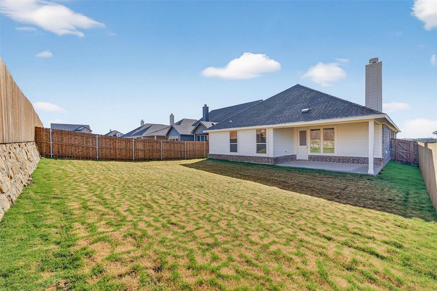Back of house with a patio, a fenced backyard, a chimney, a shingled roof, and brick siding