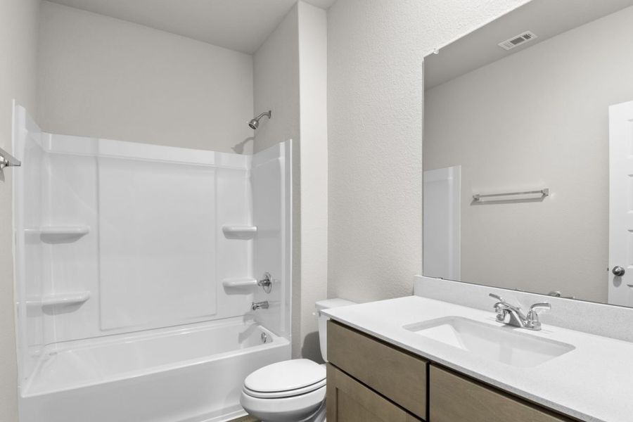 Image of a bathroom with a white vinyl shower and tub, and a white vanity with a mirror