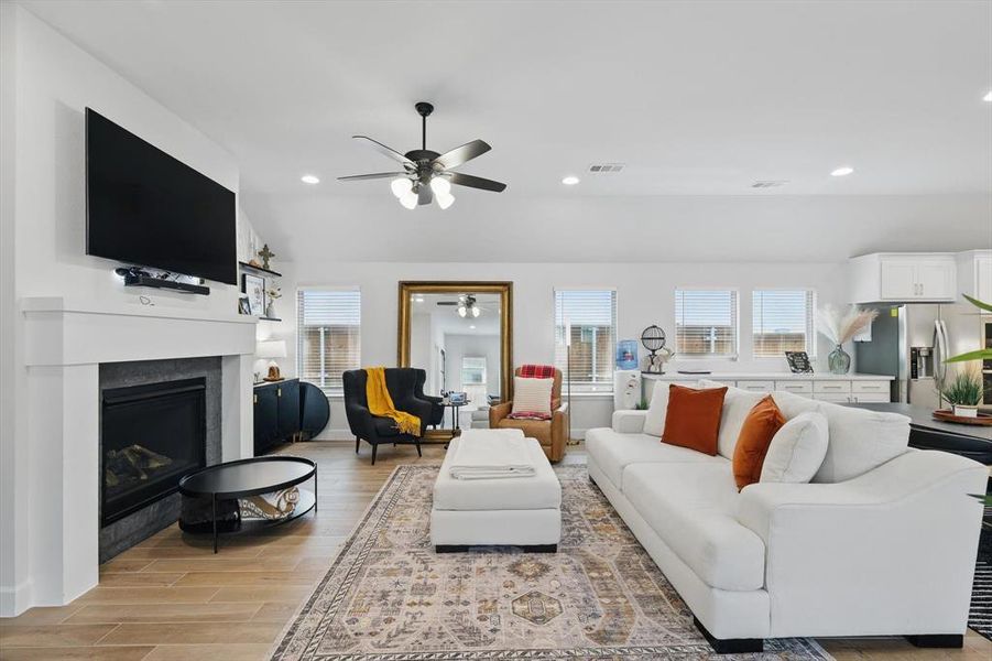 Living room with visible vents, a ceiling fan, recessed lighting, a fireplace, and light wood finished floors