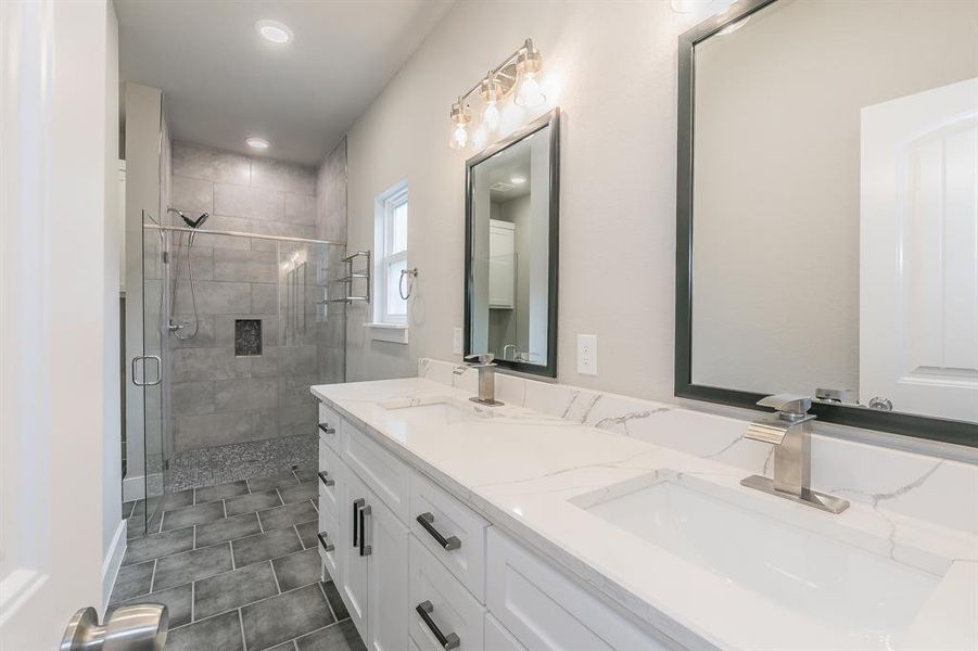 Primary Bathroom featuring double vanity, an enclosed shower, and tile flooring