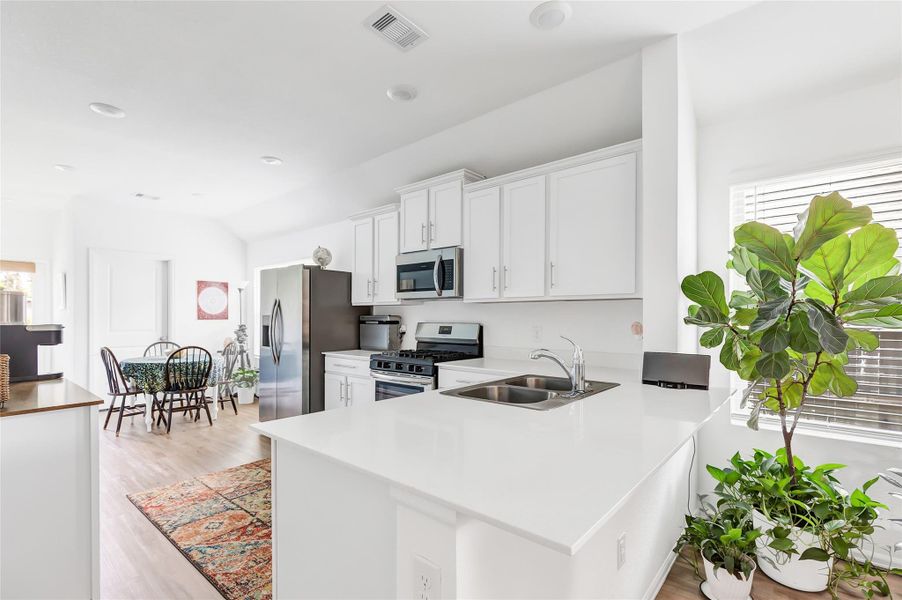 Light and bright kitchen features quartz counters, subway tile backsplash and white cabinets. It you need extra seating pull up some barstools to the breakfast bar.