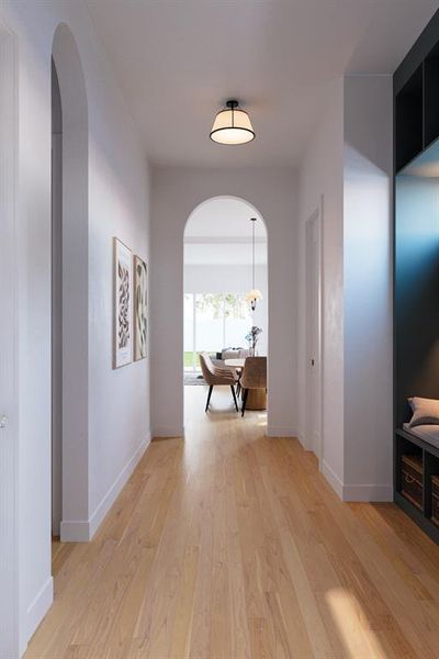 Hallway featuring arched walkways and light wood-style floors