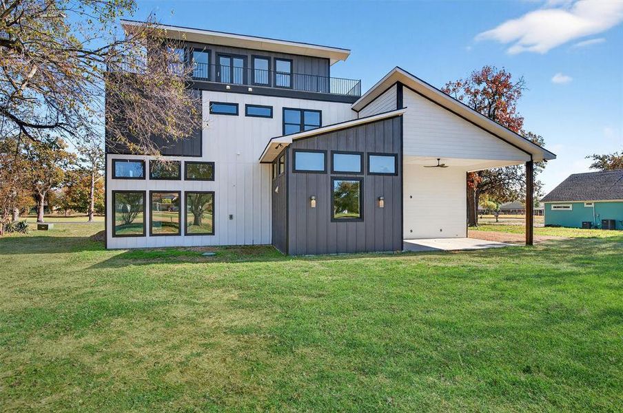 Rear view of house featuring a yard, a ceiling fan, and board and batten siding