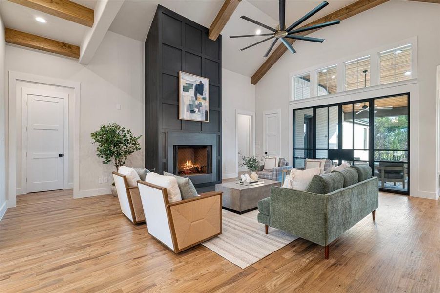 Living room featuring high vaulted ceiling, beamed ceiling, and light wood-type flooring