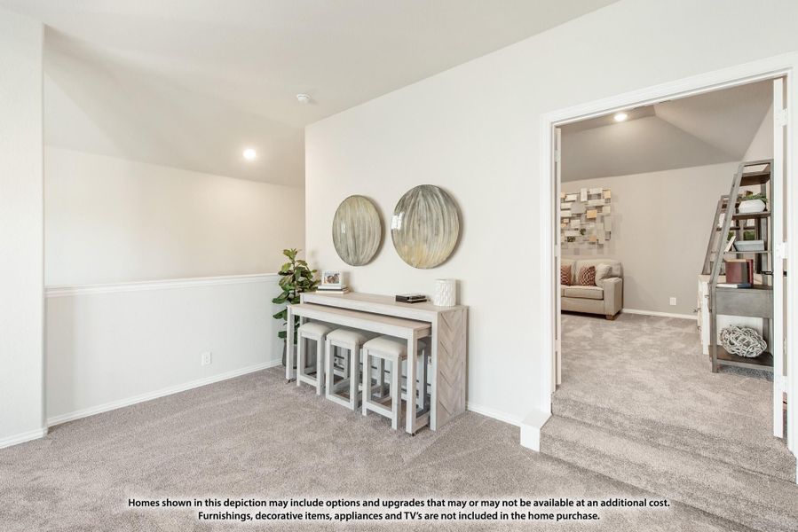 Upstairs loft area with carpet, console table, stools, and open doorway to bonus room with vaulted ceiling Upstairs loft area with carpet, console table, stools, and open doorway to bonus room with vaulted ceiling