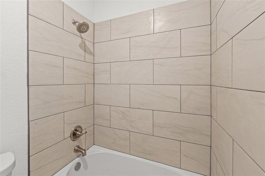 Bathroom with tiled shower / bath combo and toilet