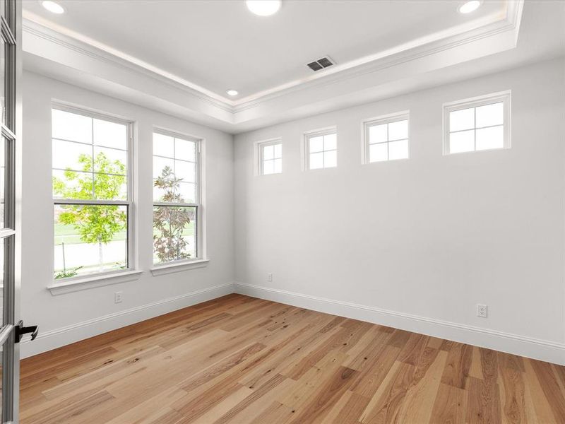 Empty room featuring a raised ceiling, light wood-style flooring, and recessed lighting
