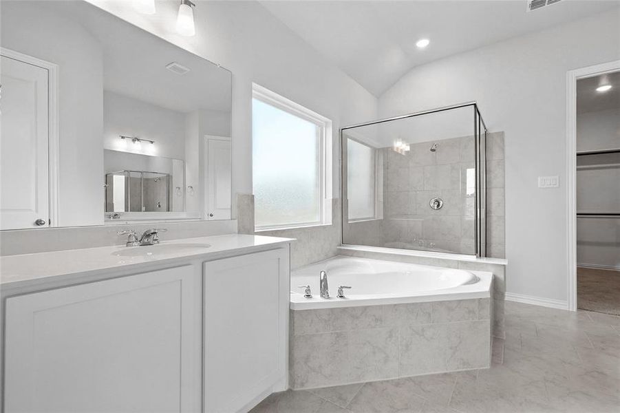 Bathroom with a garden tub, vanity, tiled shower, recessed lighting, and lofted ceiling Bathroom with a garden tub, vanity, tiled shower, recessed lighting, and lofted ceiling