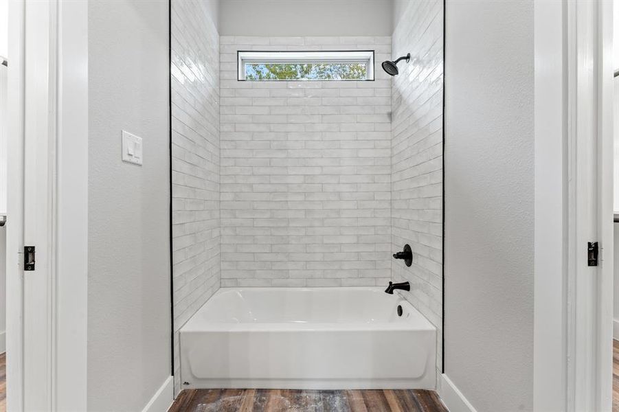 Bathroom featuring tiled shower / bath combo and hardwood / wood-style flooring