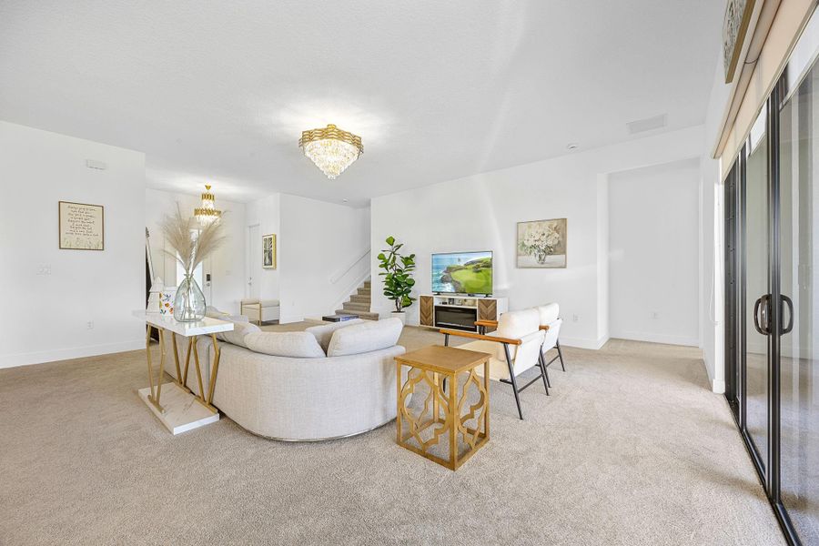 Living room featuring light colored carpet, a chandelier, and stairway