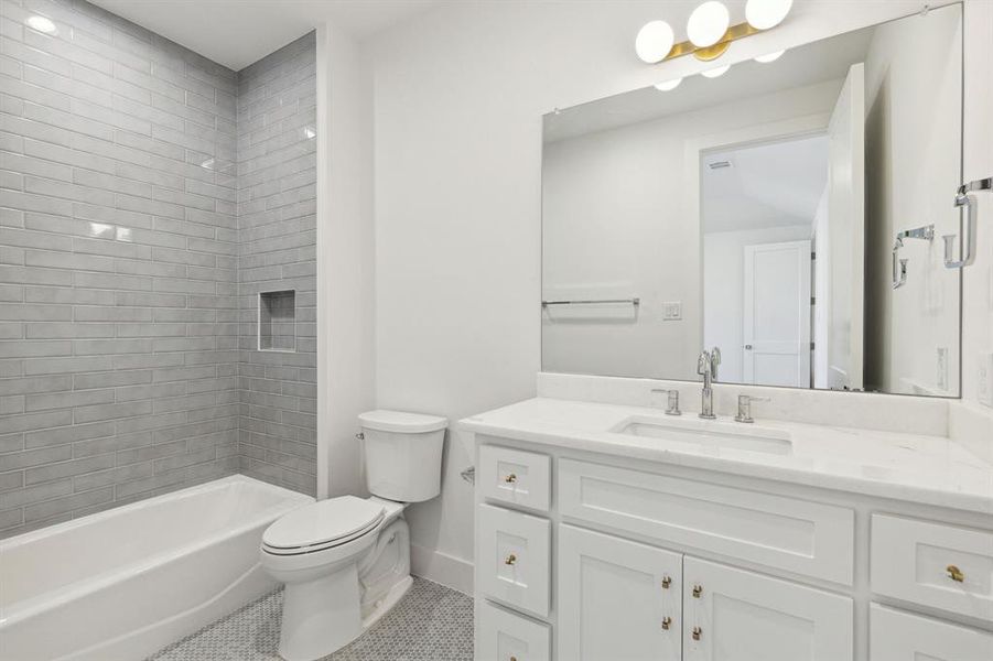 Full en suite bathroom with  glazed tiled shower / bath, vanity, tile patterned flooring, and toilet