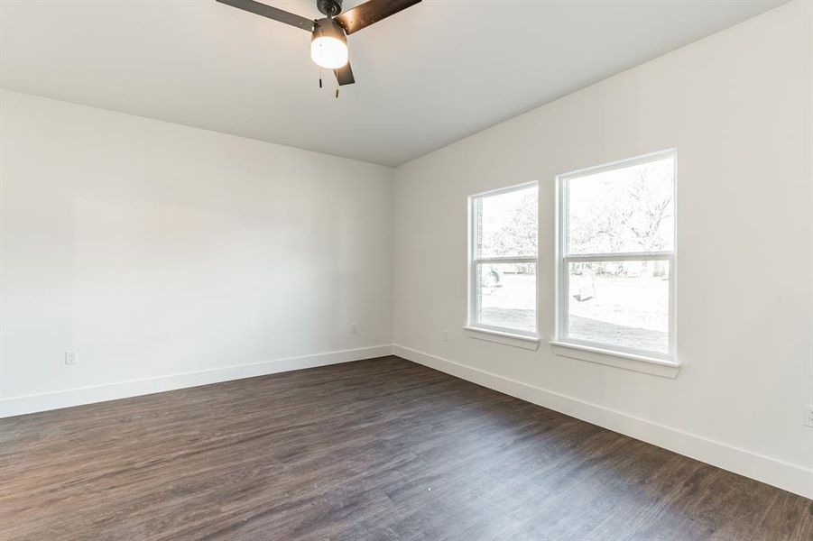 Empty room featuring dark wood-type flooring and ceiling fan