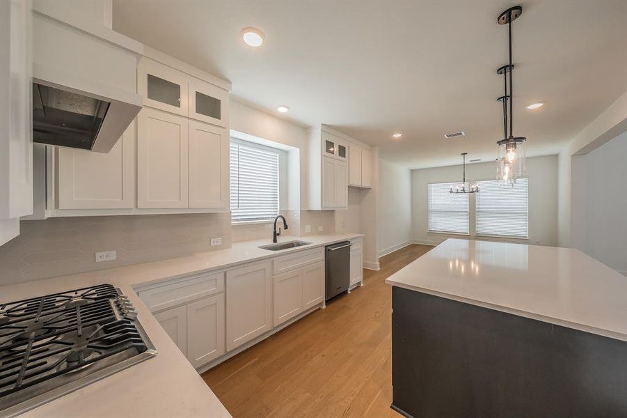 Modern kitchen featuring white cabinetry, light countertops, a gas range, stainless steel appliances, and wood flooring