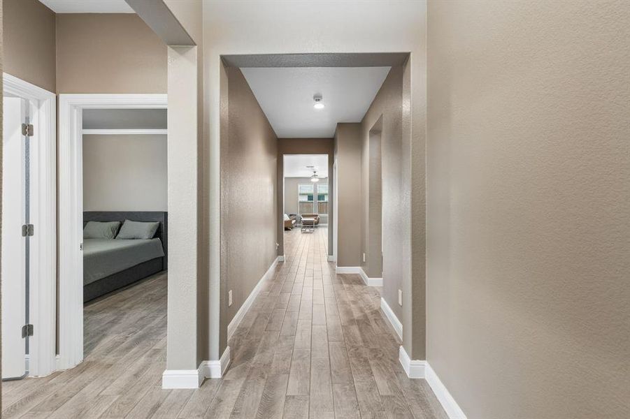 Hallway featuring wood-finish flooring, neutral wall tones, white baseboards, and recessed lighting