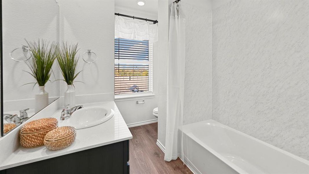 Bathroom with vanity, dark wood-style floors, and shower / bathtub combination with curtain