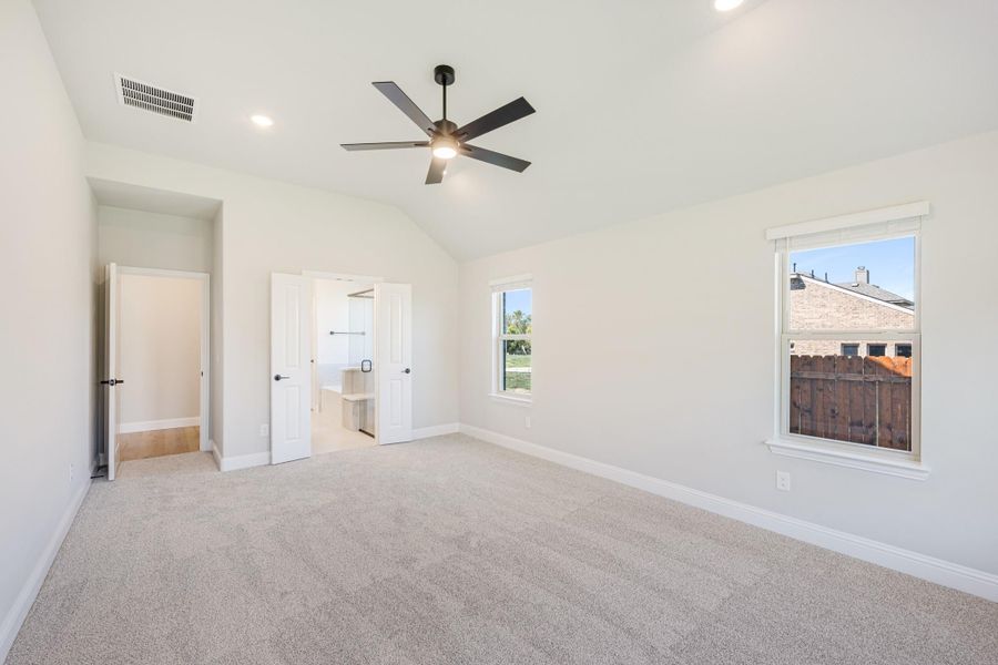 Empty bedroom with vaulted ceiling, ceiling fan, carpet flooring, and open walk-in closet Empty bedroom with vaulted ceiling, ceiling fan, carpet flooring, and open walk-in closet