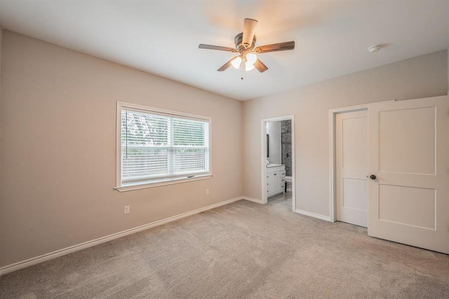 Unfurnished bedroom featuring ensuite bath, light carpet, and ceiling fan Unfurnished bedroom featuring ensuite bath, light carpet, and ceiling fan