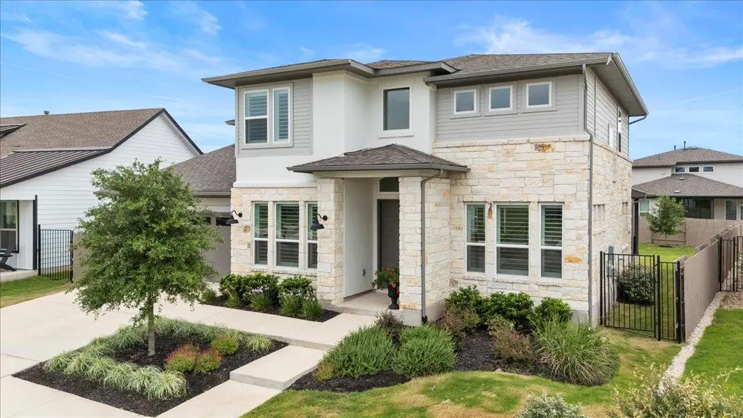 Prairie-style house with stone siding, a shingled roof, and a gate