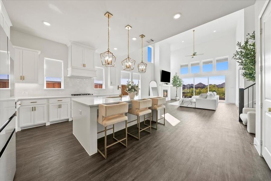 Kitchen with gas stovetop, white cabinetry, an island with sink, premium range hood, and a kitchen breakfast bar