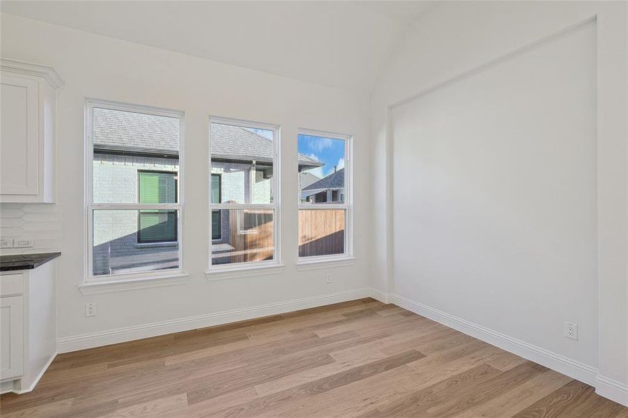 Unfurnished dining area featuring lofted ceiling and light hardwood / wood-style floors