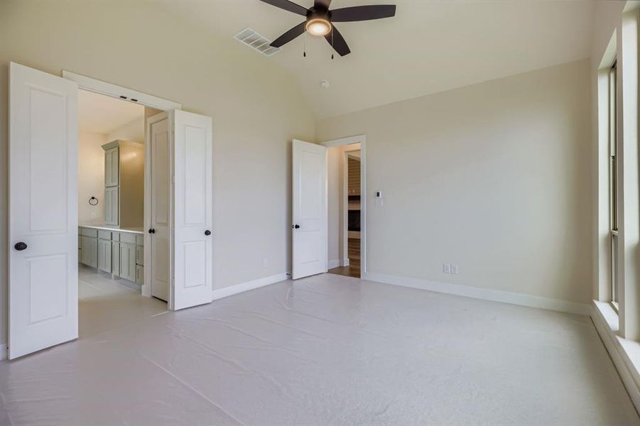 Unfurnished bedroom featuring lofted ceiling, light carpet, a ceiling fan, and connected bathroom Unfurnished bedroom featuring lofted ceiling, light carpet, a ceiling fan, and connected bathroom