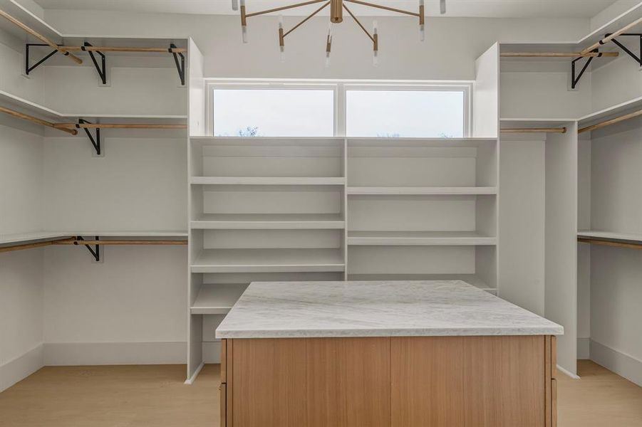 Walk in closet with light wood-style flooring and a chandelier