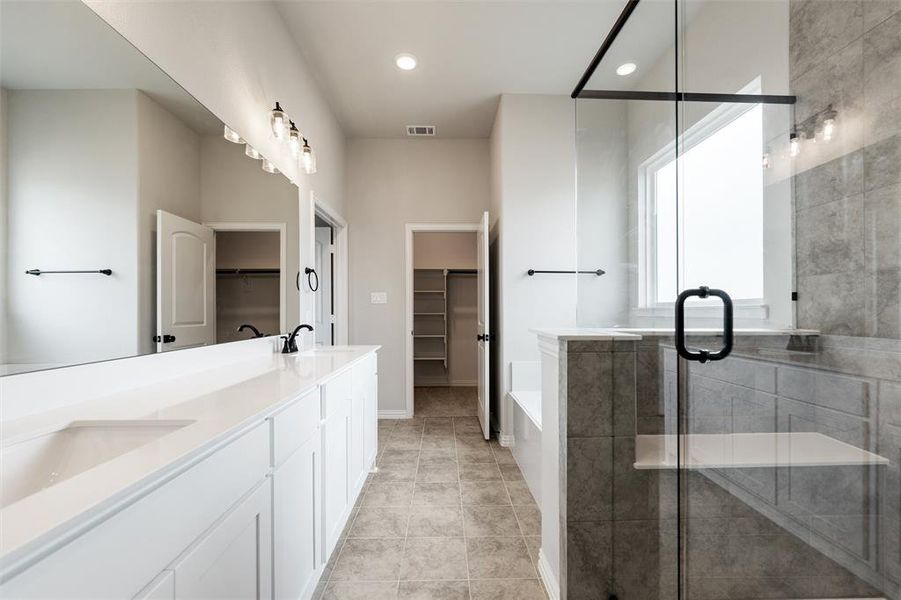 Bathroom featuring a spacious closet, a garden tub, double vanity, a shower stall, and recessed lighting Bathroom featuring a spacious closet, a garden tub, double vanity, a shower stall, and recessed lighting