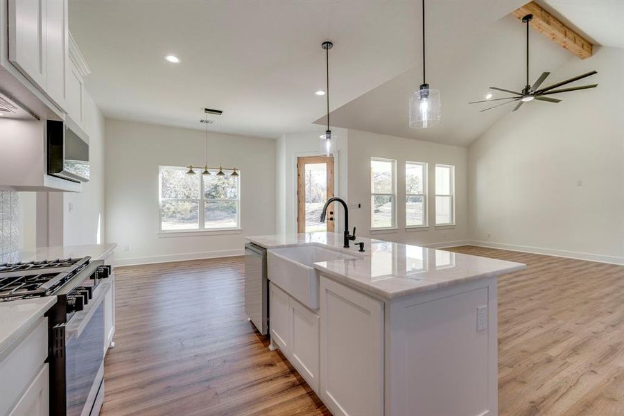 Kitchen featuring white cabinetry, a kitchen island with sink, gas range, dishwasher, and sink