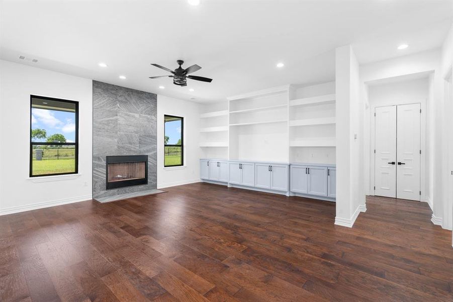 Unfurnished living room with recessed lighting, ceiling fan, a premium fireplace, and dark wood finished floors Unfurnished living room with recessed lighting, ceiling fan, a premium fireplace, and dark wood finished floors