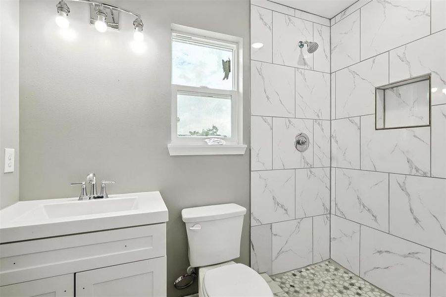 Bathroom featuring a tile shower and vanity Bathroom featuring a tile shower and vanity